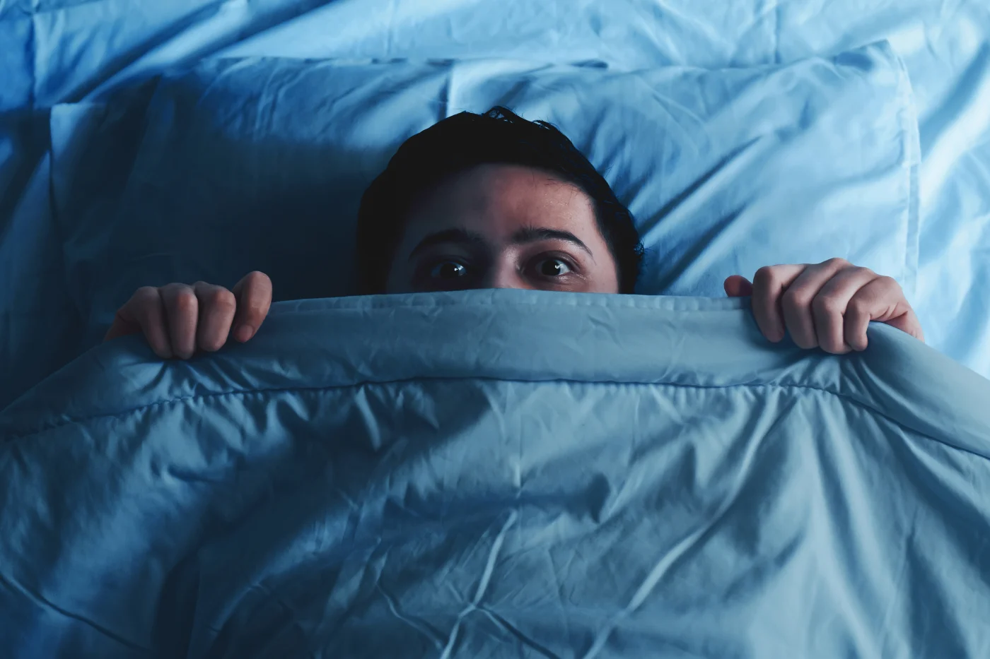 Local Barndominium Truss Supplier In The Kansas City Area | North Country Truss A man gripping and peeking above the blankets, having just awakened from a nightmare.